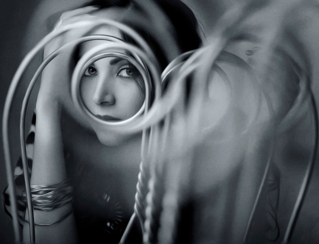 Services An artistic black and white portrait featuring a woman framed with spirals and blurred foreground elements.